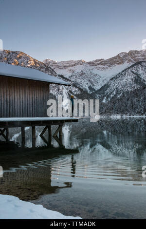 Vista laterale di uomo in piedi sul molo sul lago contro il cielo chiaro al forest Foto Stock