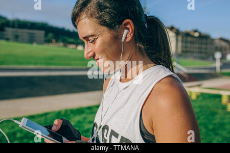 Vista laterale della donna usando il telefono in posizione di parcheggio Foto Stock