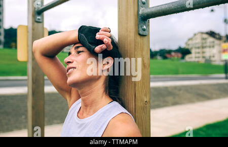 Premurosa donna appoggiata contro la ginnastica bar del park Foto Stock