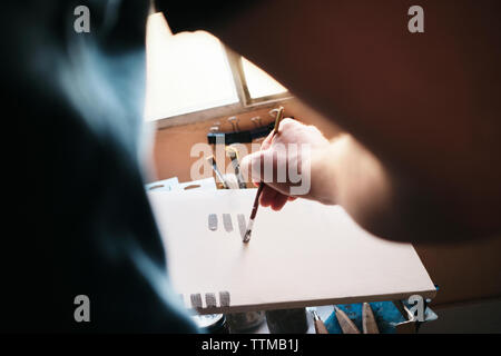 Artista maschile test di vernice acrilica e pennello su tela per il nuovo lavoro Foto Stock