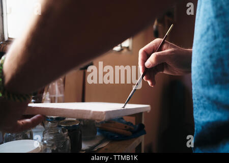 Artista maschile test di vernice acrilica e pennello su tela per il nuovo lavoro Foto Stock