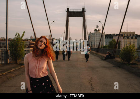 La ragazza con i capelli rossi camminando sul ponte in città Foto Stock