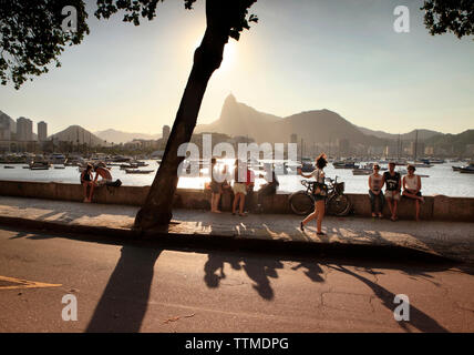 Il Brasile, Rio de Janeiro, Bar Urca, persone a sedersi su una parete del mare sull'Oceano Atlantico Foto Stock