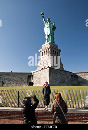 Stati Uniti d'America, New York, una donna con la sua fotografia scattata di fronte alla statua della Libertà Foto Stock