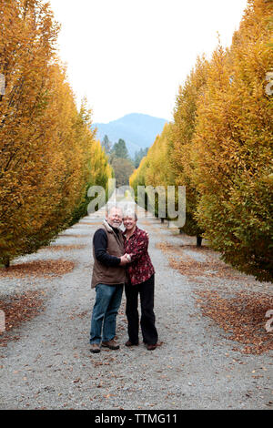 Stati Uniti d'America, Oregon, Medford, Cal e Judy Schmidt stand tra gli alberi della loro azienda, Schmidt famiglia vigneti è situato nella bellissima valle Applegate ha Foto Stock