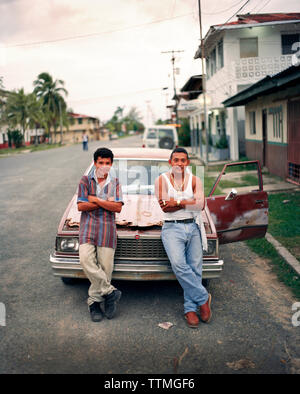 PANAMA, PANAMA, Bocas del Toro, giovani uomini in appoggio contro la loro auto sulla strada principale, America Centrale Foto Stock