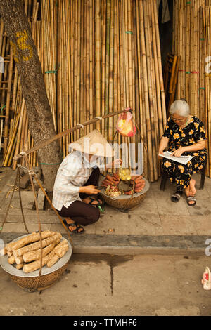 Il Vietnam, Hanoi, un venditore ambulante vende ortaggi a radice sul bambù street nella città vecchia Foto Stock