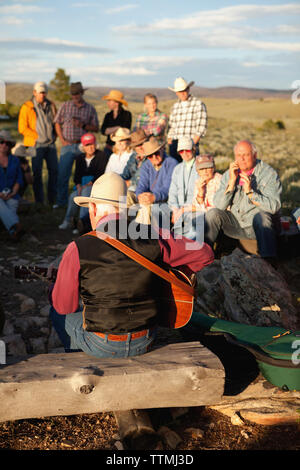 Stati Uniti d'America, Wyoming Encampment, gli ospiti di un dude ranch sedersi intorno a un falò e ascoltare un uomo suonare la chitarra e cantare canzoni country western, Abara Ranch Foto Stock