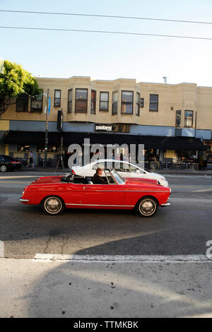 Stati Uniti, California, San Francisco, un uomo aziona un vecchio classico auto giù Columbus Ave. in North Beach Foto Stock