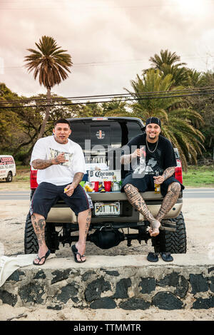 Stati Uniti d'America, Oahu, Hawaii, Daytyn Ragragola e Kenneth Meyer Jr. sedersi sul retro di un enorme pickup truck sulla North Shore a Haliewa Beach Park Foto Stock