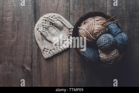 Vista aerea del cappello in maglia di lana da sfere nella ciotola sul tavolo Foto Stock