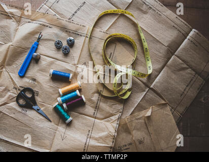 Angolo di alta vista di elementi di cucitura con le carte sul tavolo in officina Foto Stock