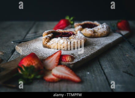 Crostate con fette di fragola sul tavolo di legno su sfondo nero Foto Stock