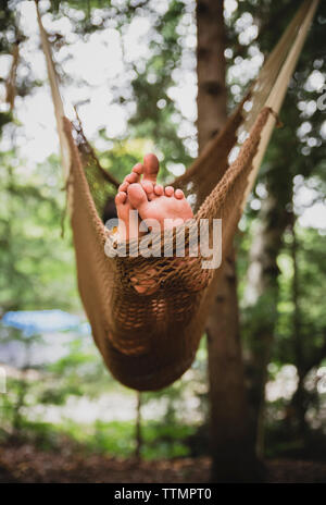 Sezione bassa del ragazzo sul rilassante amaca in foresta Foto Stock