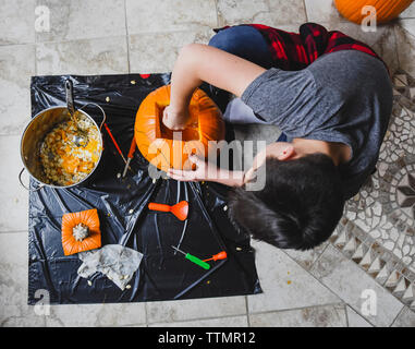 Angolo di Alta Vista del ragazzo rimuovendo i semi di zucca in casa Foto Stock