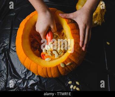 Mani tagliate la rimozione di semi di zucca a casa Foto Stock