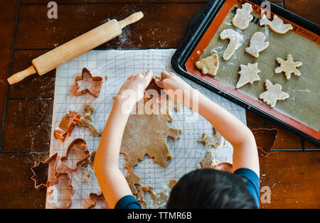 Colpo di overhead del bambino le mani rendendo i cookie utilizzando cookie cutter. Foto Stock