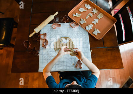 Colpo di overhead del bambino sta facendo i cookie con cookie cutter. Foto Stock