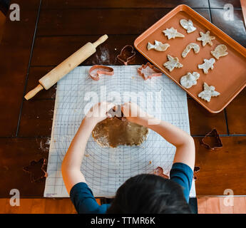 Colpo di overhead del bambino sta facendo i cookie con cookie cutter. Foto Stock