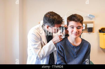 Medico cercando in orecchio di adolescenti ad un paziente in una camera di esame. Foto Stock