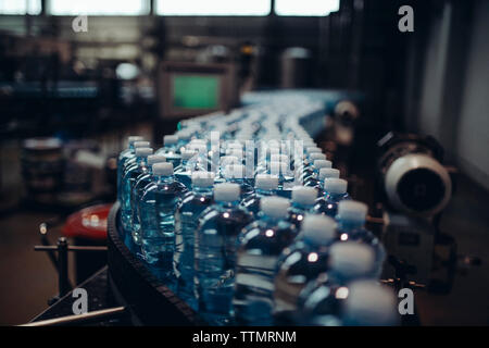 Close-up di bottiglie di acqua sul nastro trasportatore in fabbrica Foto Stock