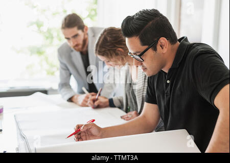 I colleghi rendendo blueprint in office Foto Stock