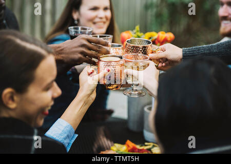 Angolo di alta vista di happy amici tostare un drink seduti nel cortile posteriore Foto Stock