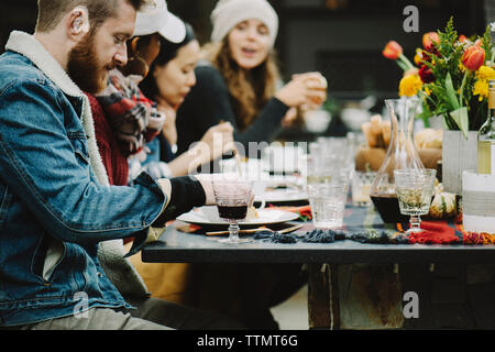 Amici gustando pasti a tavola in cortile Foto Stock