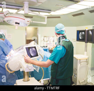 Vista posteriore del chirurgo a lavorare con i colleghi in sala operatoria Foto Stock
