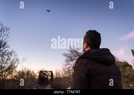 L'uomo Flying drone contro sky durante il tramonto Foto Stock