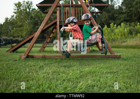 Giocoso fratelli oscillanti in parco giochi Foto Stock