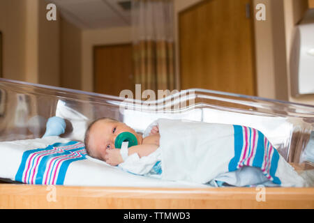 Ritratto di bambino con il succhietto nella bocca giacente nel presepe in ospedale Foto Stock