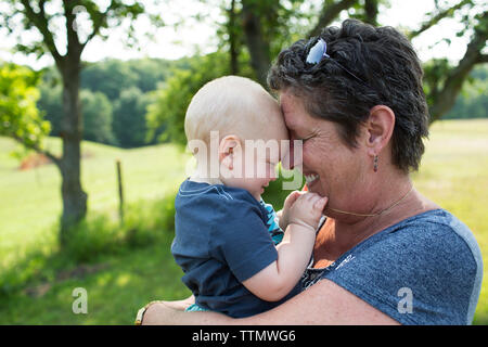 Close-up di nonna nipote di trasporto mentre si sta in piedi sul campo nel parco Foto Stock