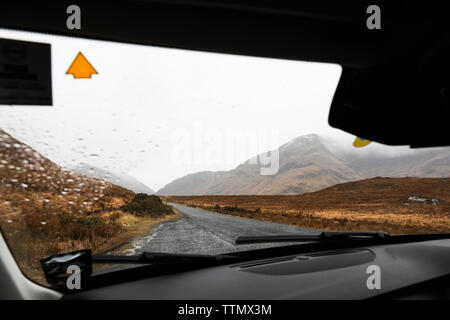 Vista della strada irlandese e montagne attraverso il parabrezza di pioggia Foto Stock