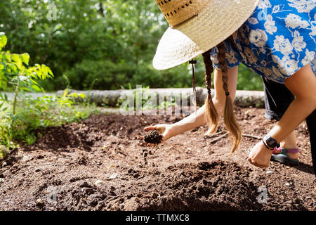 Donna flessione durante l'analisi della qualità del suolo sul campo Foto Stock