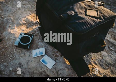 Elevato angolo di visione della telecamera con instant fotografie e bagagli sulla formazione di roccia durante il tramonto Foto Stock