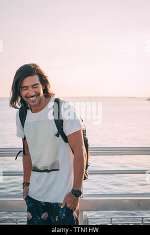 Il brasiliano di ridere su un molo al tramonto con vista sul mare Foto Stock