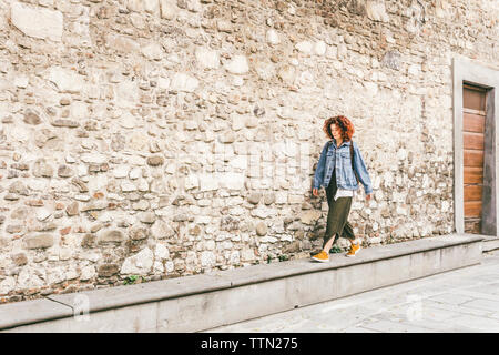 Donna che cammina sul sentiero dal vecchio edificio in città Foto Stock