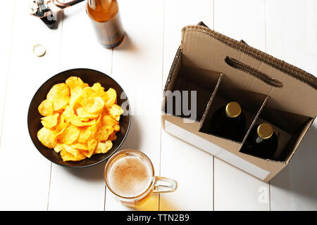 Carta pacchetto di birra con tazza e chip su sfondo di legno Foto Stock