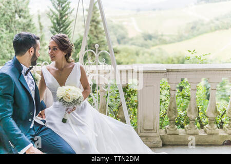 Romantico sposa giovane guardando gli uni con gli altri mentre seduto su swing Foto Stock