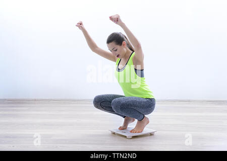 Donna di celebrare un weightloss raggiungimento degli obiettivi su una scala a casa Foto Stock