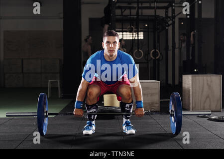 Ritratto di determinata atleta maschio il sollevamento barbell in palestra Foto Stock