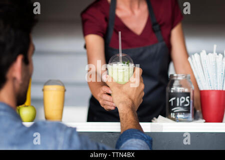 Sezione mediana del proprietario femmina frullato dando al cliente al cibo carrello Foto Stock