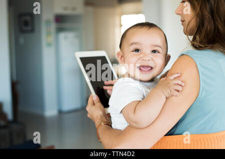 Madre che trasportano baby boy in carrier durante l'utilizzo di tablet pc Foto Stock