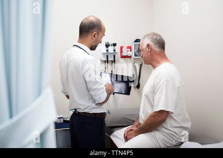 Medico mostra x-ray rapporti in computer tablet per paziente in ospedale Foto Stock
