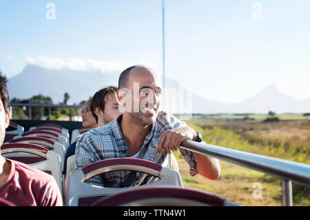 I turisti in cerca di vista mentre si è in viaggio in autobus a due piani contro sky Foto Stock