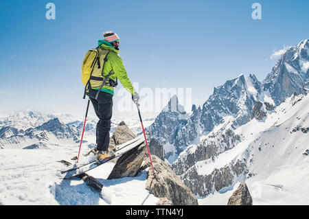 Escursionista con gli sci in piedi sulla coperta di neve montagna contro il cielo blu e chiaro durante la giornata di sole Foto Stock