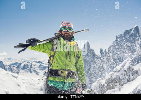 Escursionista con gli sci in piedi sulla coperta di neve montagna contro il cielo chiaro durante la giornata di sole Foto Stock