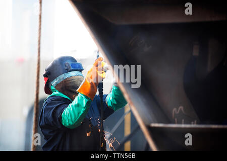 Lavoratore contenitore di saldatura nave presso l'industria Foto Stock