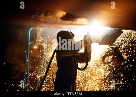 Vista laterale del lavoratore la saldatura ala di aeroplano di notte Foto Stock